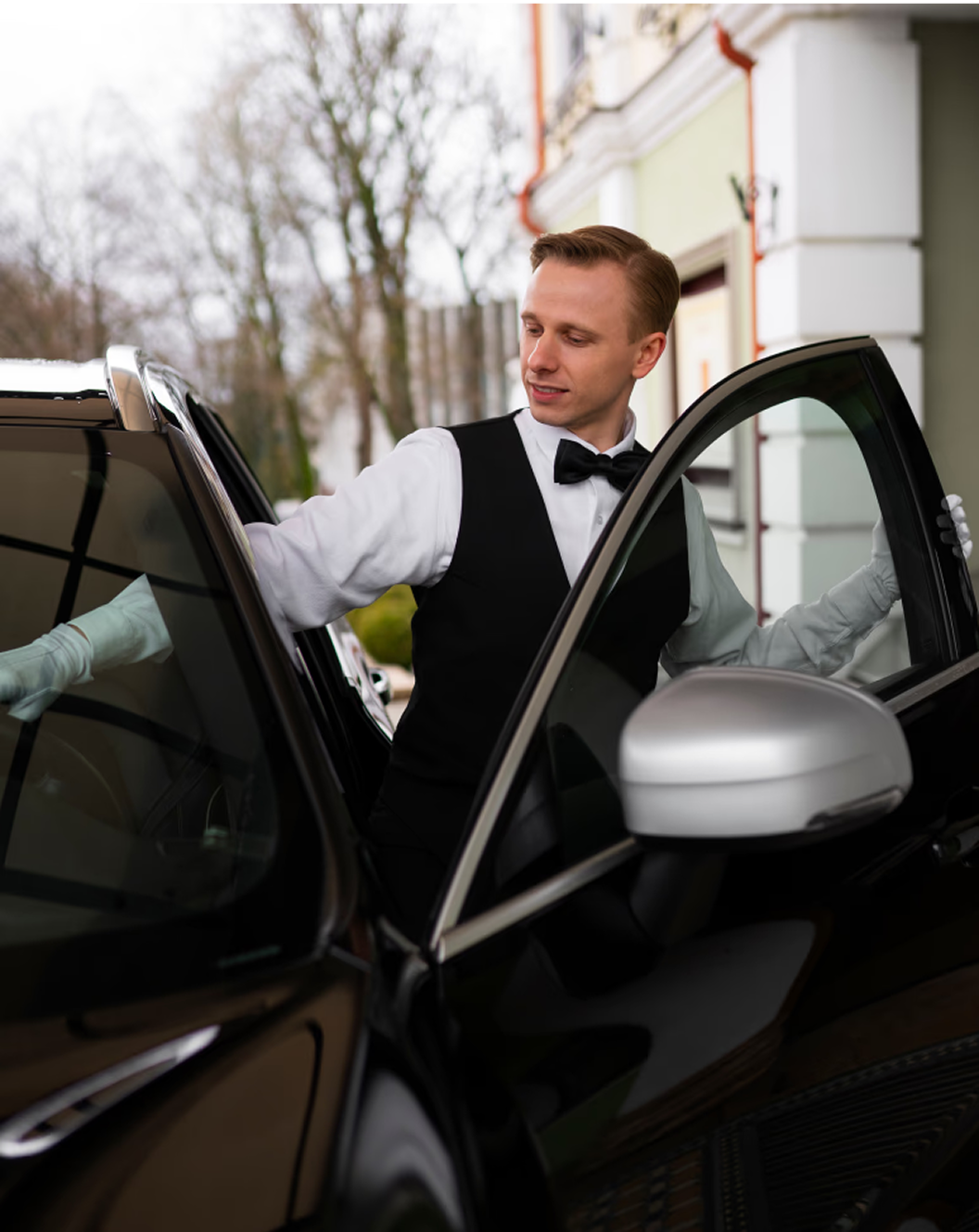 Professional chauffeur in formal uniform standing beside luxury sedan ready to serve